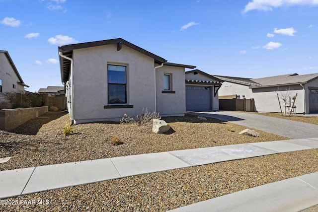 ranch-style house with stucco siding, driveway, an attached garage, and fence