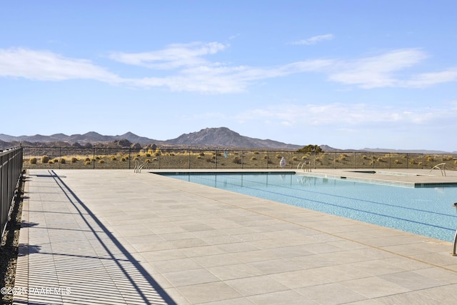 community pool featuring a patio area, a mountain view, and fence