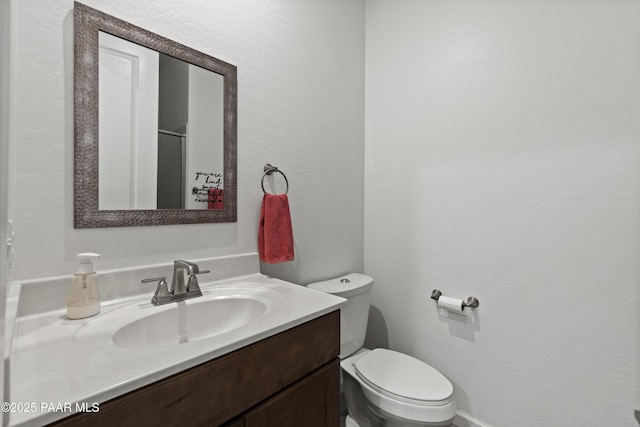 bathroom featuring a shower with door, toilet, and vanity