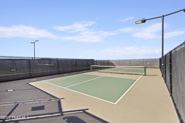 view of tennis court with community basketball court and fence