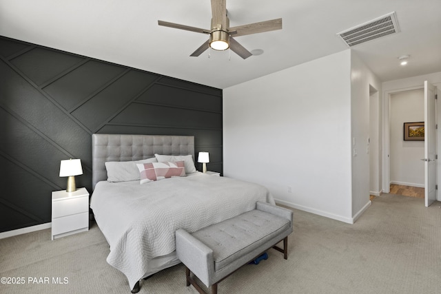 bedroom with light carpet, visible vents, a decorative wall, and baseboards