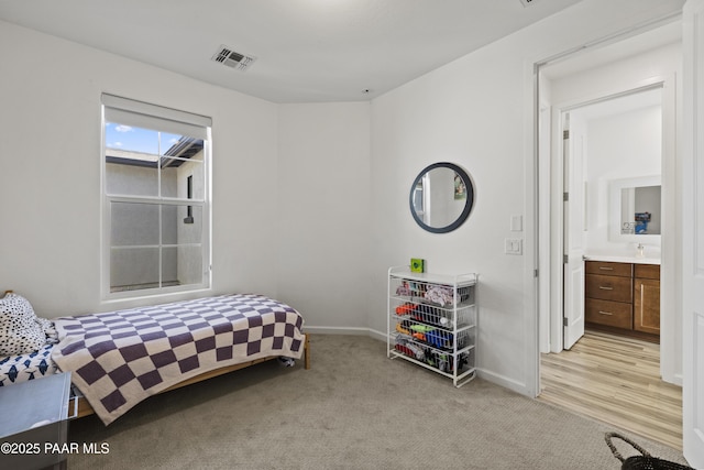 bedroom with a sink, light colored carpet, visible vents, and baseboards