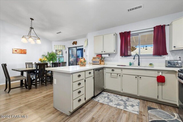 kitchen with stainless steel dishwasher, vaulted ceiling, sink, pendant lighting, and light hardwood / wood-style floors