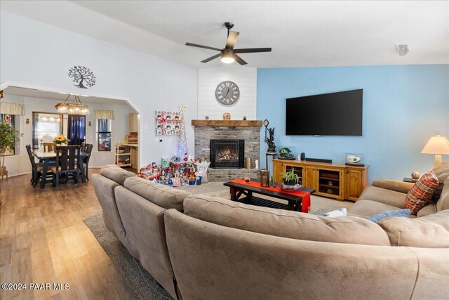 living room with hardwood / wood-style flooring, ceiling fan with notable chandelier, and vaulted ceiling