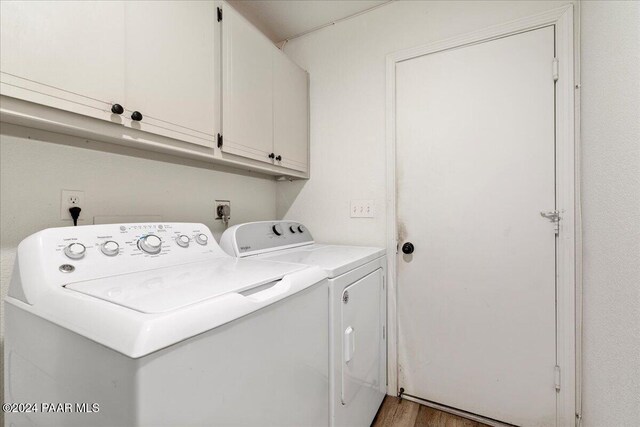 laundry room with washer and clothes dryer, cabinets, and hardwood / wood-style flooring