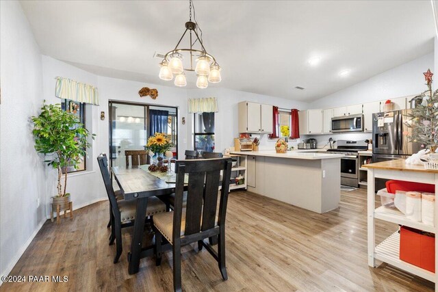 dining room featuring light hardwood / wood-style floors, lofted ceiling, and an inviting chandelier