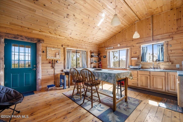 dining area with light hardwood / wood-style floors, plenty of natural light, wooden ceiling, and wood walls