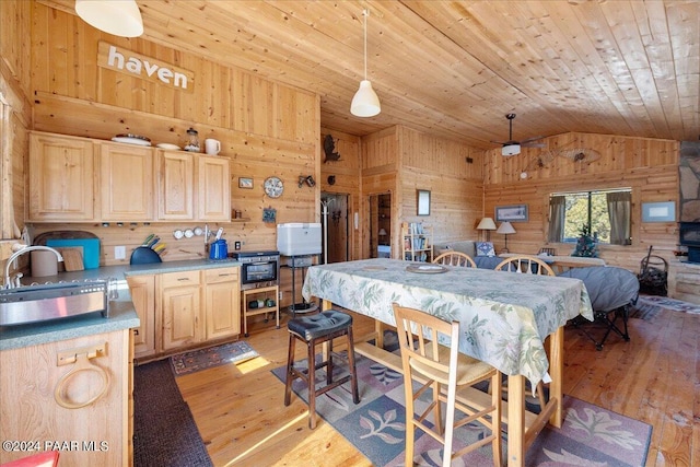 dining area with wood walls, light hardwood / wood-style floors, lofted ceiling, and sink