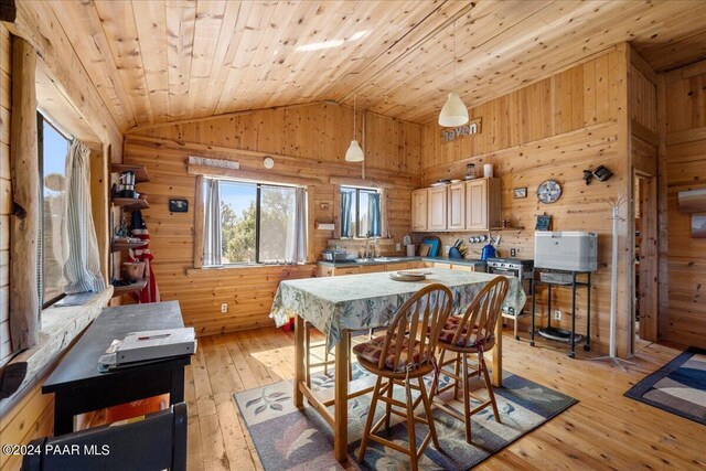 dining space featuring vaulted ceiling, sink, wooden ceiling, light hardwood / wood-style floors, and wood walls