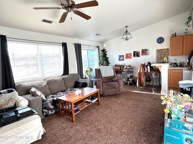 living room with ceiling fan with notable chandelier and dark carpet