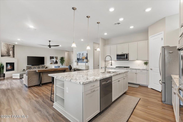 kitchen with a ceiling fan, visible vents, appliances with stainless steel finishes, a sink, and white cabinets