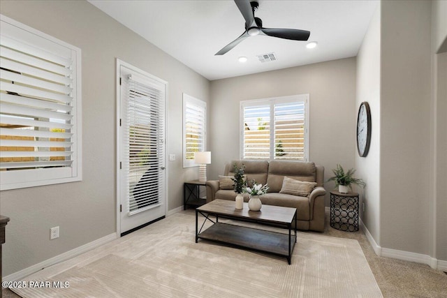 living room featuring baseboards, a ceiling fan, light colored carpet, and visible vents