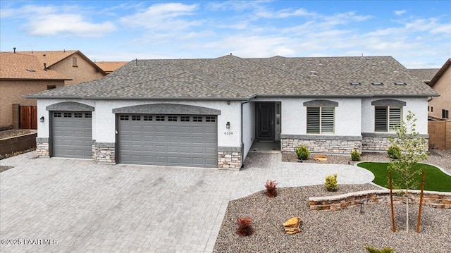 ranch-style home with roof with shingles, stone siding, a garage, stucco siding, and decorative driveway