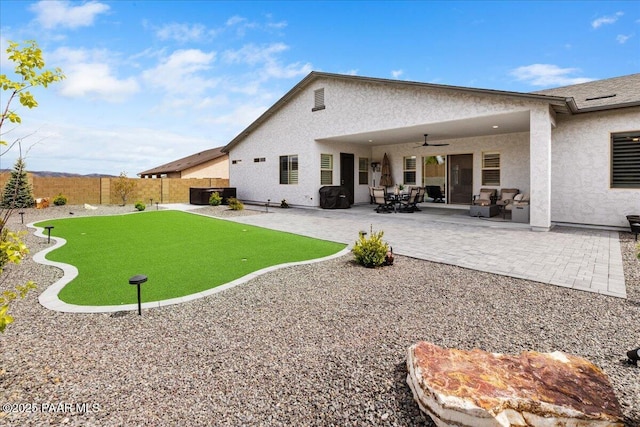 back of house with ceiling fan, a fenced backyard, a patio area, and stucco siding