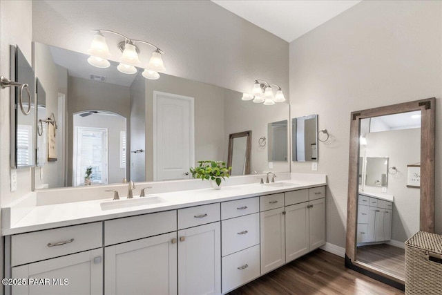full bath featuring a sink, visible vents, double vanity, and wood finished floors