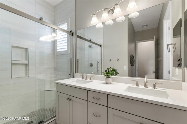 full bath featuring a sink, a stall shower, double vanity, and visible vents