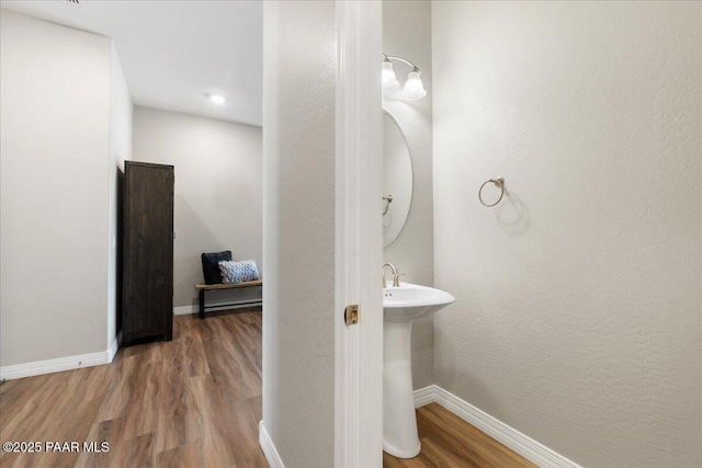 bathroom featuring baseboards, a sink, and wood finished floors