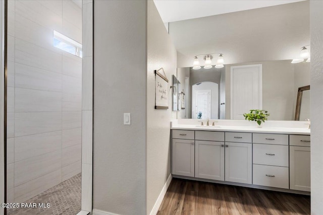 full bath with vanity, baseboards, walk in shower, and wood finished floors
