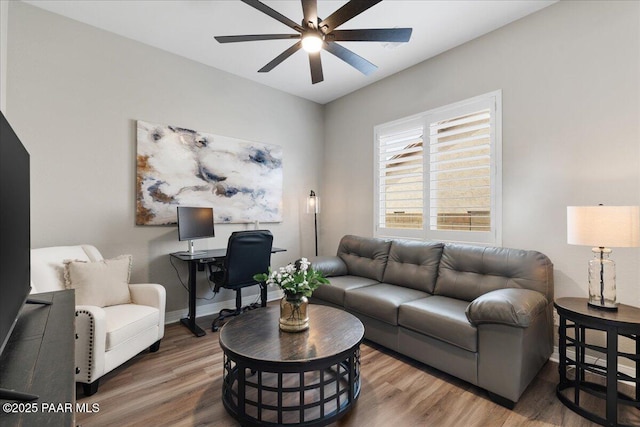 living area with baseboards, a ceiling fan, and wood finished floors