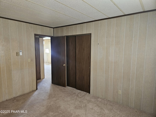 unfurnished bedroom with light carpet and wood walls