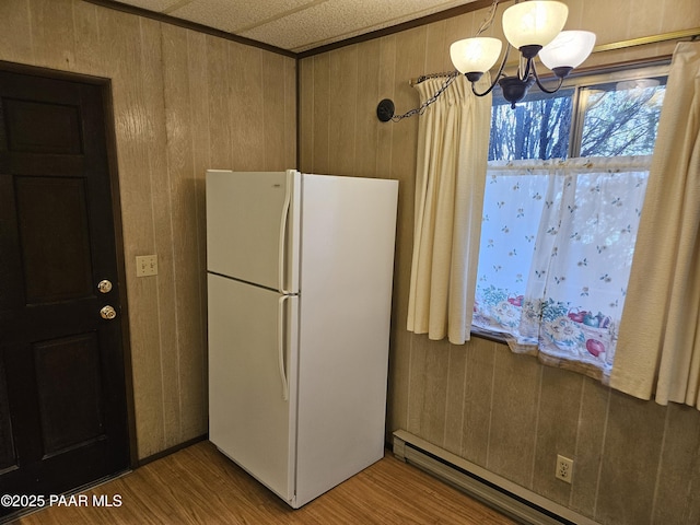 kitchen with a baseboard radiator, white fridge, hardwood / wood-style floors, and wood walls