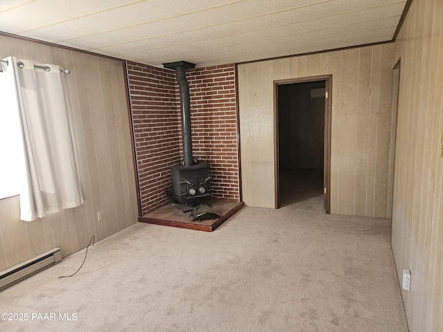 unfurnished living room with a baseboard radiator, light colored carpet, wood walls, and a wood stove