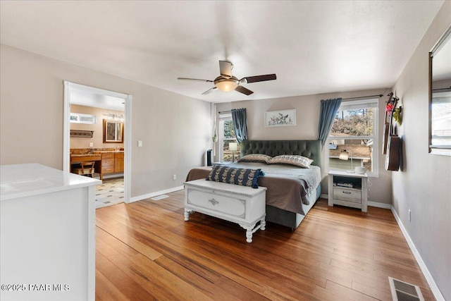 bedroom featuring hardwood / wood-style flooring, ceiling fan, ensuite bathroom, and multiple windows