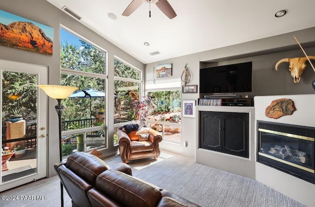 carpeted living room with ceiling fan and vaulted ceiling