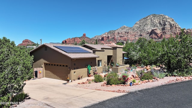 view of front facade with a mountain view, a garage, and solar panels