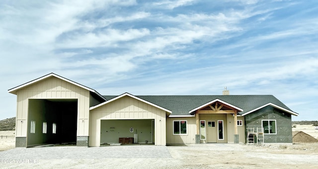 view of front of house with driveway, an attached garage, a chimney, and a shingled roof