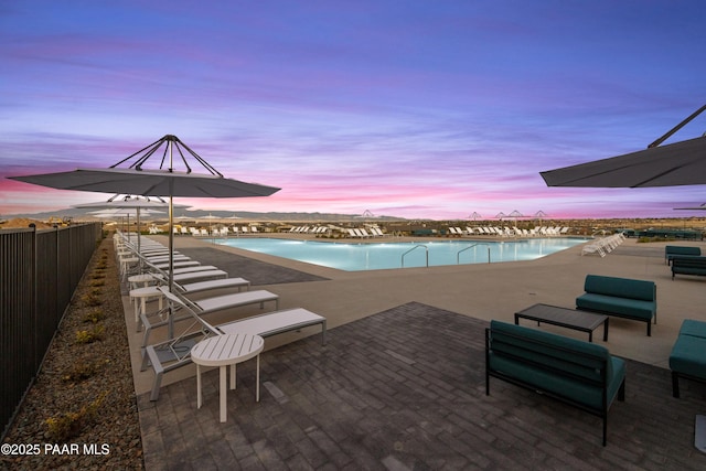 pool at dusk with a patio area