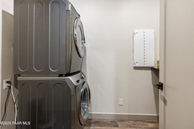 laundry area with stacked washer and dryer and dark hardwood / wood-style floors