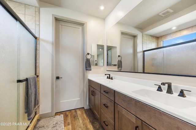 bathroom with hardwood / wood-style flooring, vanity, and walk in shower