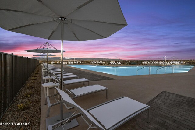 pool at dusk featuring a patio