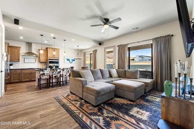 living room featuring sink, ceiling fan with notable chandelier, and light hardwood / wood-style floors