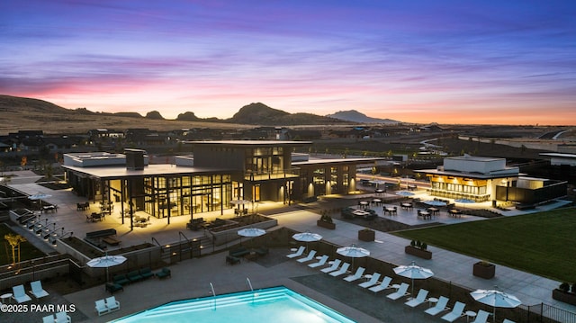 pool at dusk featuring a mountain view and a patio area