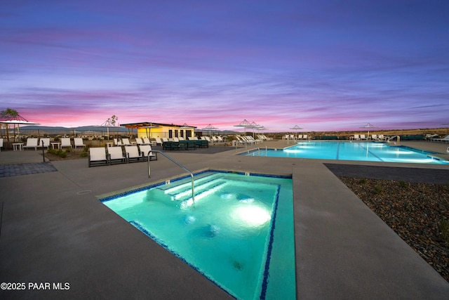 pool at dusk featuring a community hot tub and a patio area