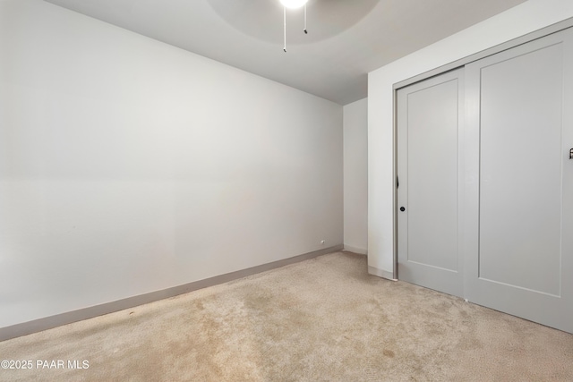 unfurnished bedroom featuring light carpet, ceiling fan, and a closet