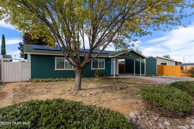 single story home featuring solar panels and a carport