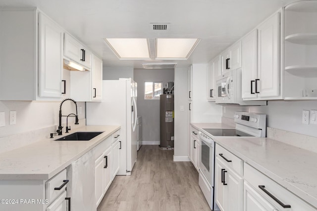 kitchen with a skylight, white cabinetry, sink, and white appliances