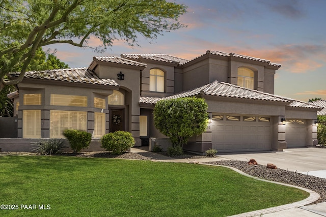 mediterranean / spanish-style home with concrete driveway, a lawn, a tiled roof, an attached garage, and stucco siding