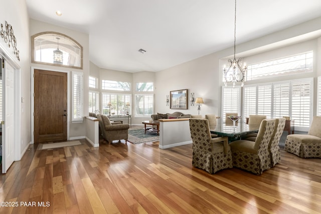 foyer with light wood-style floors, a towering ceiling, baseboards, and a notable chandelier
