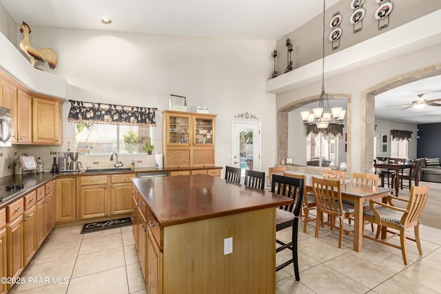 kitchen with tasteful backsplash, dark countertops, a sink, light tile patterned floors, and a breakfast bar area