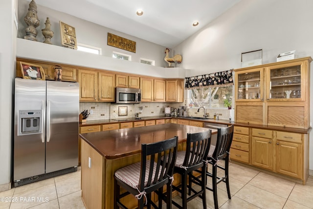 kitchen with high vaulted ceiling, dark countertops, light tile patterned floors, backsplash, and appliances with stainless steel finishes