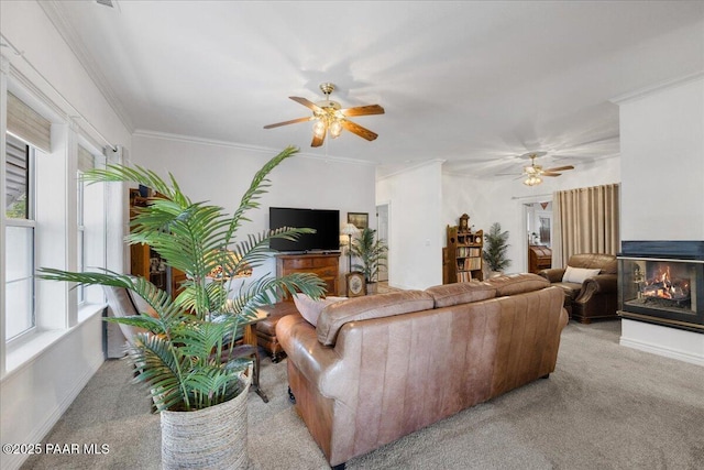 living room with ceiling fan, light colored carpet, a multi sided fireplace, and ornamental molding