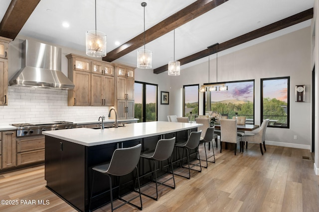 15425 N Talking Rock Ranch Rd, Prescott, AZ 86305 - kitchen with wall chimney exhaust hood, stainless steel gas cooktop, backsplash, light countertops, and a center island with sink