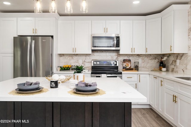 kitchen featuring white cabinetry, a kitchen island, decorative light fixtures, and appliances with stainless steel finishes