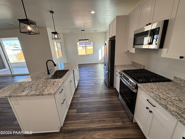 kitchen featuring appliances with stainless steel finishes, decorative light fixtures, a kitchen island with sink, and sink