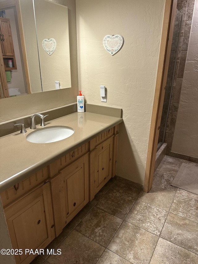13502 S Burton Rd, Mayer, AZ 86333 - bathroom featuring vanity, a textured wall, stone tile flooring, and a stall shower