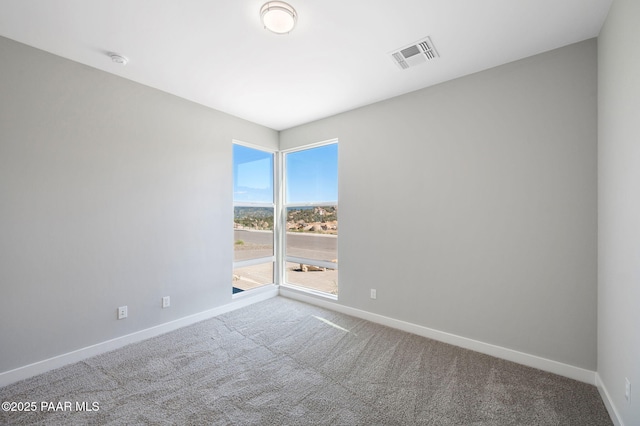 carpeted spare room featuring baseboards and visible vents